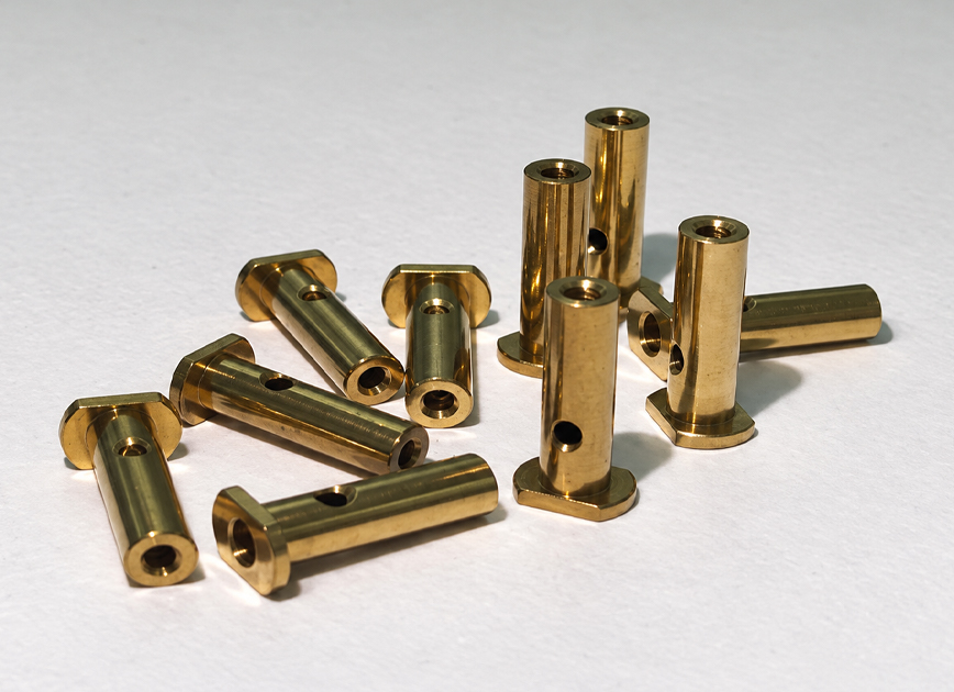 Brass cylindrical components with flanged ends, axial bores and cross-holes